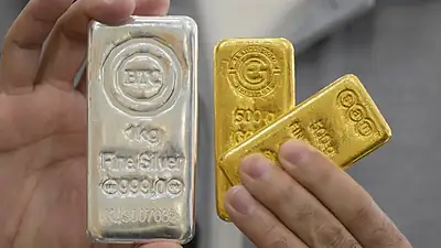 زەڕەنگەرێک لە دوکانەکەیدا پارچەی زێڕ و زیو نیشان دەدات