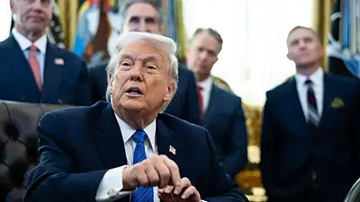دۆناڵد ترەمپ لە وێنەکەدا لە نووسینگەی هێلکەیی لە پشت مێزەکەی دانیشتووە. چاکەتێکی ڕەش، کراسێکی سپی، بۆینباخێکی شین و ڕۆزێتێکی ئاڵای ئەمەریکای لەبەردایە. لە پشتیشیەوە چوار بەرپرسی پیاو بە قاتەوە وەستاون.